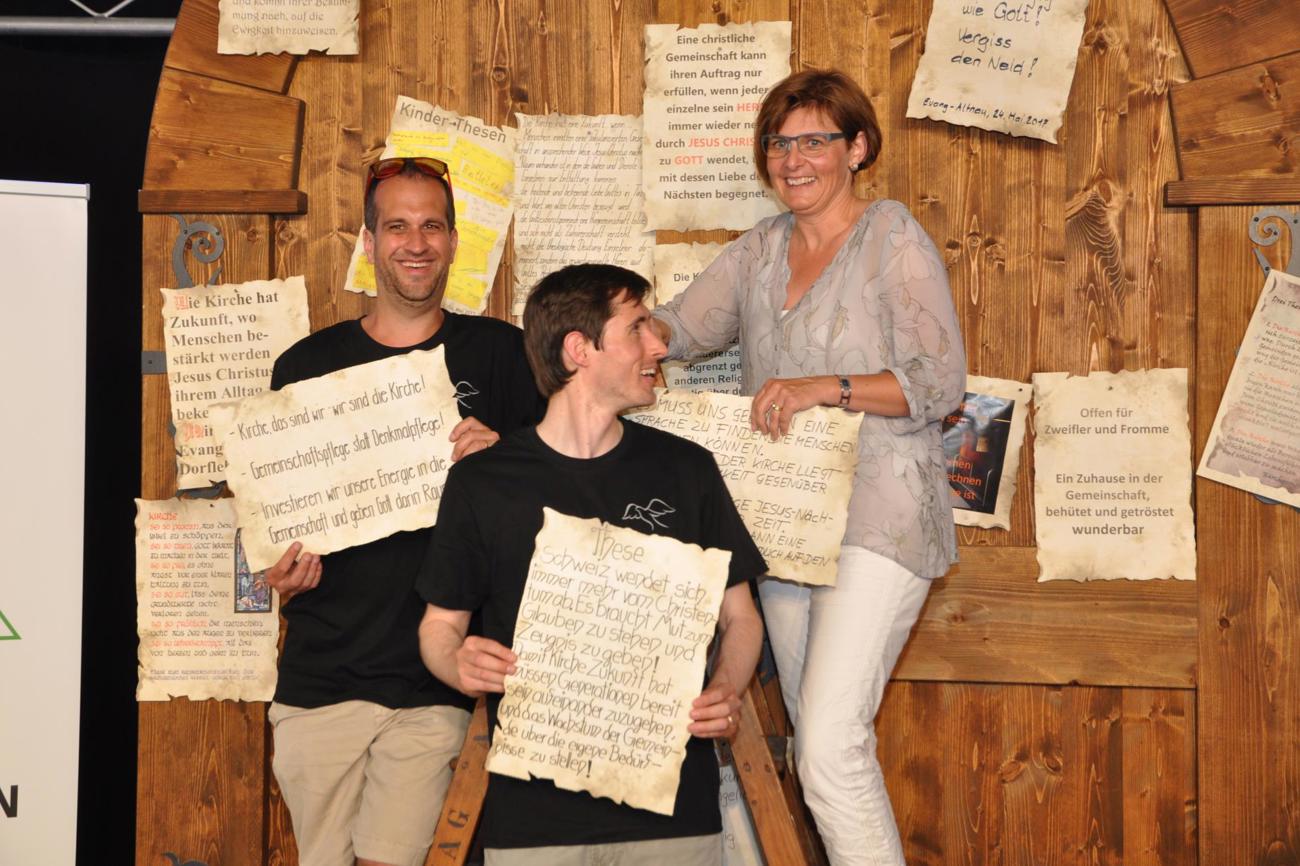 Matthias Hüberli aus Egnach, Pfarrer Matthias Maywald aus Neukirch an der Thur und Monika Brauchli aus Alterswilen präsentieren ihre Thesen vor der Kirchentür.