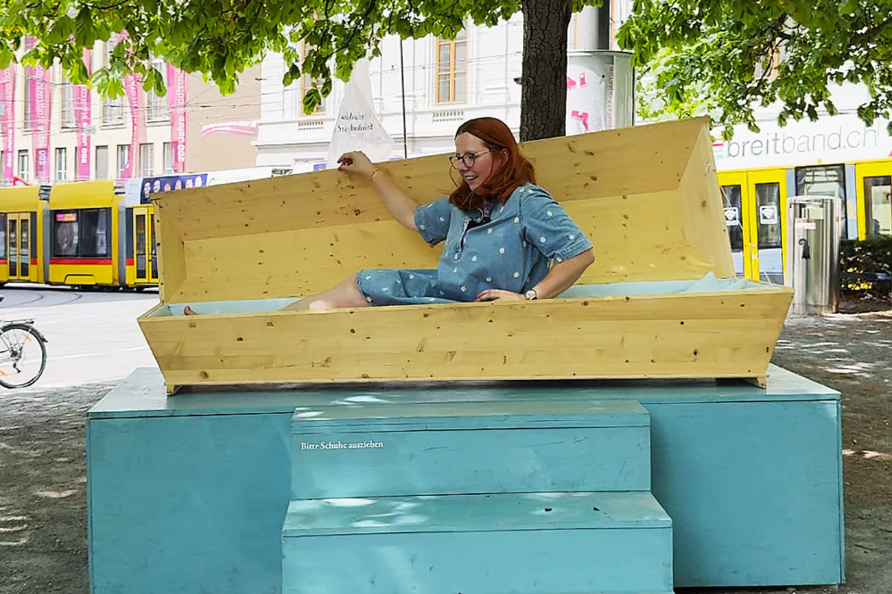 Mitten auf dem Theaterplatz in Basel: Noemi Harnickell legt sich in den Sarg der Ausstellung «Sterbensmutig» und erzählt, wie es sich anfühlt. | Foto: Nicole Noelle