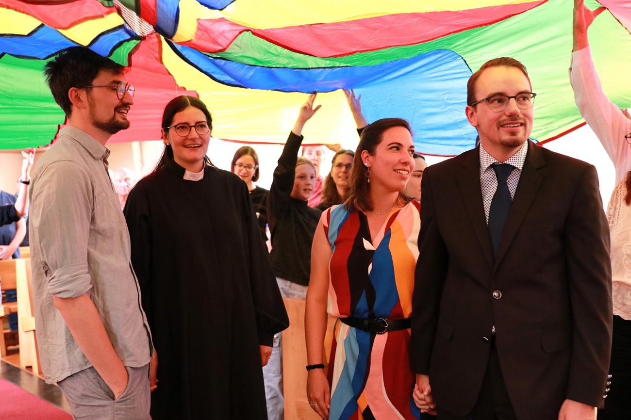 Aylin Weets (zweite von links) und Micha Rippert (ganz rechts) standen zum Schluss des Ordinationsgottesdienstes unter einen farbigen Fallschirm. (Bild: Claudia Koch)