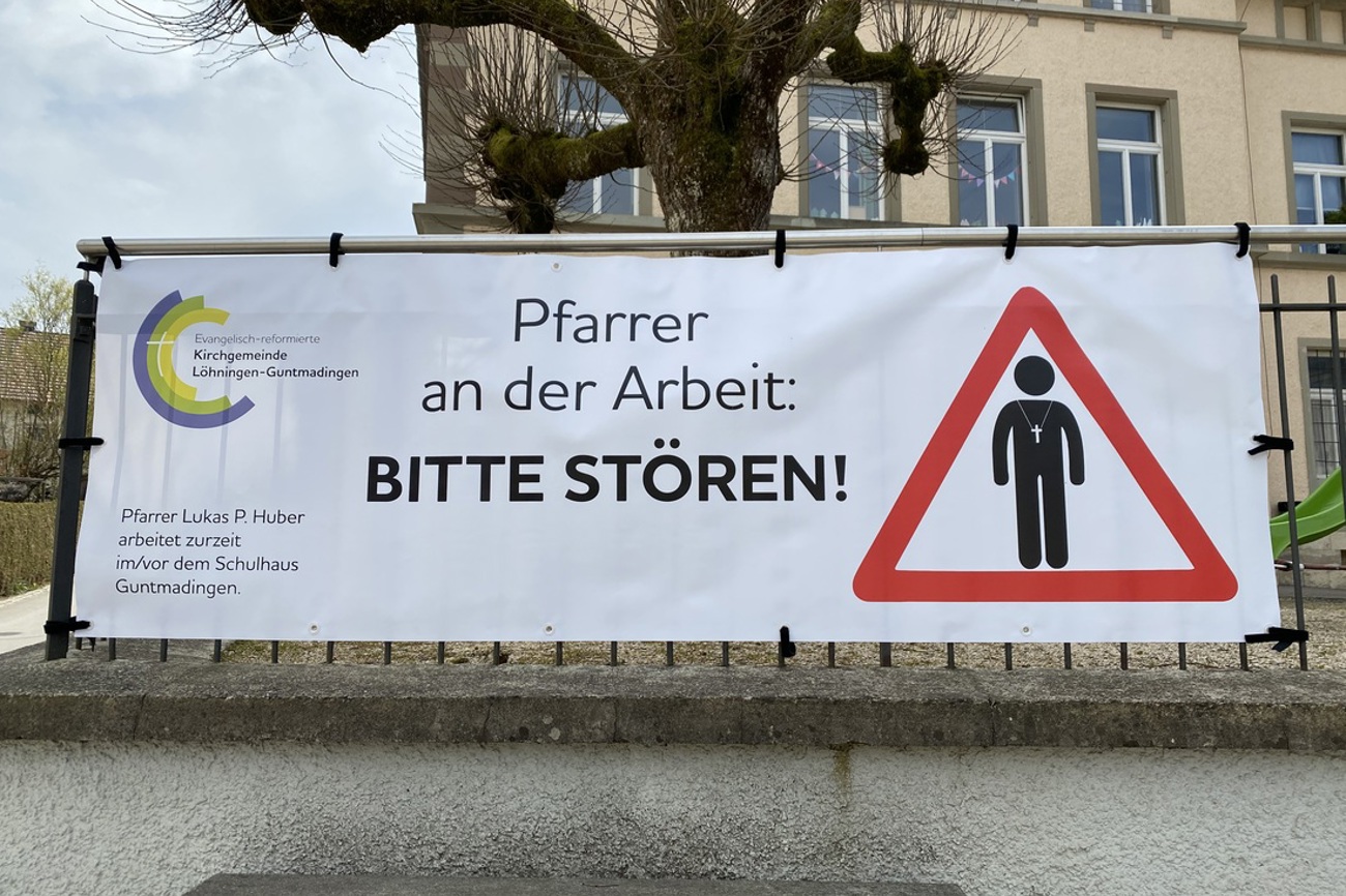 Ein ungewohntes Plakat, das Aufmerksamkeit erregt: Das "Pfarrer an der Arbeit: Bitte stören!"-Plakat, hier vor dem Schulhaus Guntmadingen. (Bild: zVg)