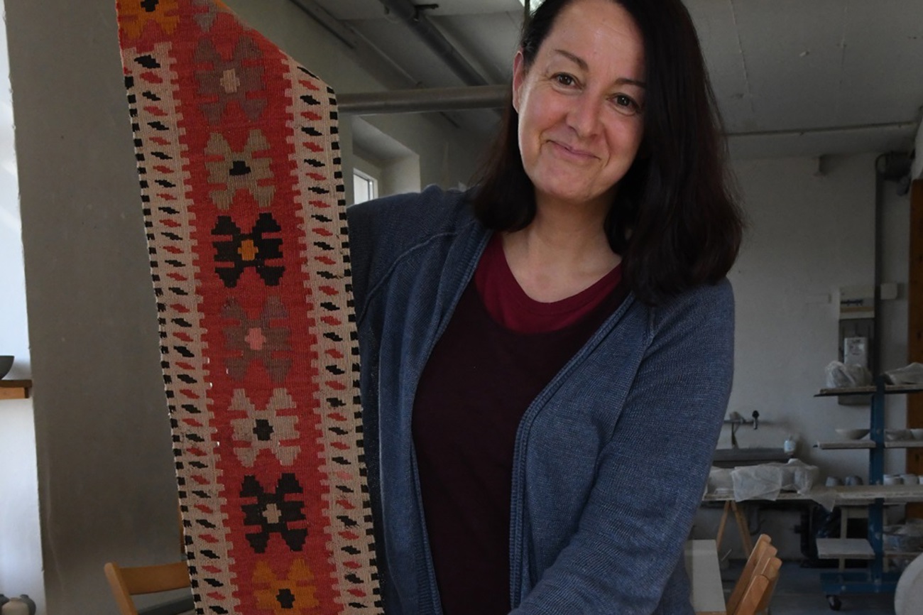 Kathrin Ritzi, Präsidentin des Vereins Little Bridge Schweiz, präsentiert einen handgewobenen Tischläufer aus Bergkarabach. (Bild: zVg)