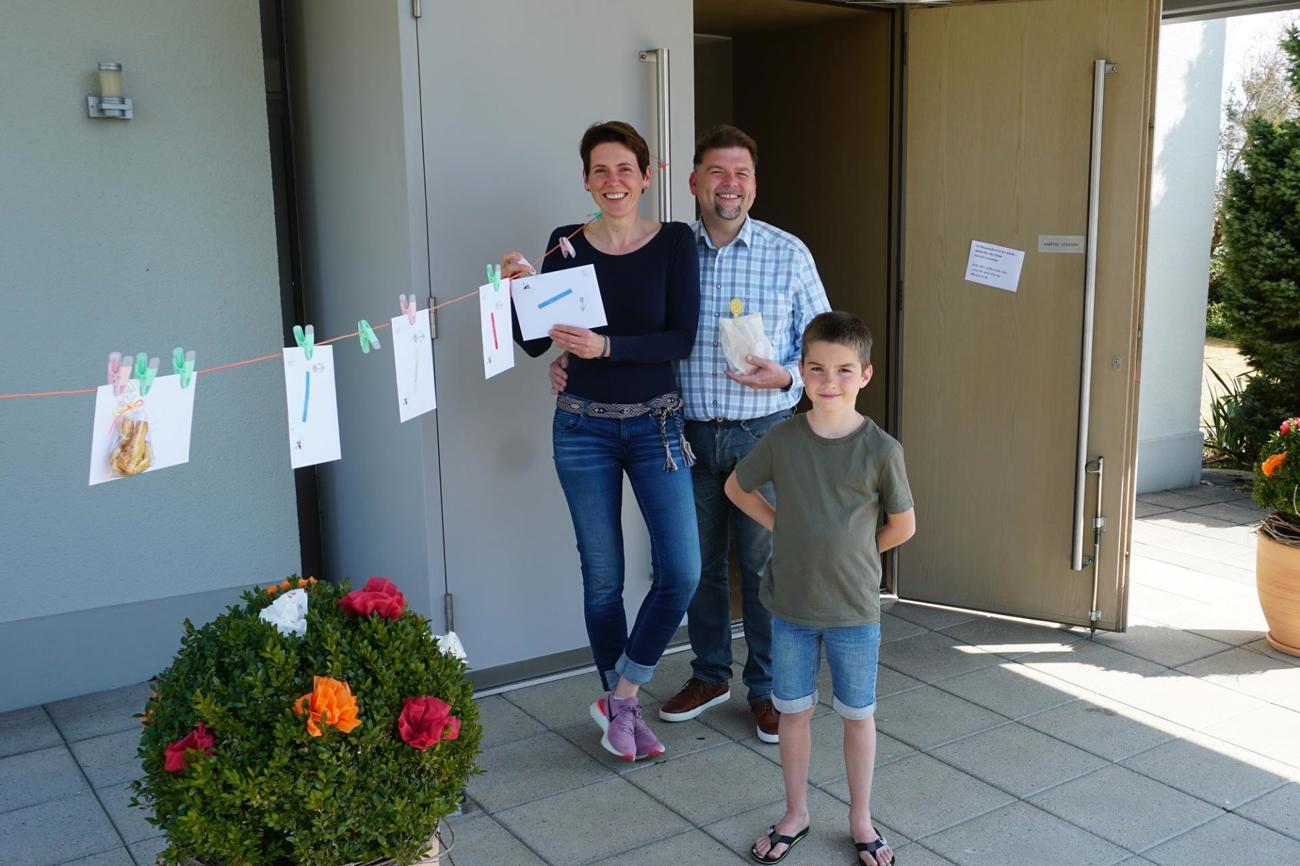Katharina und Michael Wentkowski mit «Gottibueb» Samuel Heynen freuen sich über die «Gottesdienst-Wäscheleine
» vor der Kirche Wigoltingen: Die kreative Idee des Pfarrers hat bei Gemeindemitgliedern weitere Einfälle ausgelöst
– zum Beispiel die Guetzli links aussen, die als Dank zusätzlich aufgehängt wurden. (Bild: Lars Heynen)