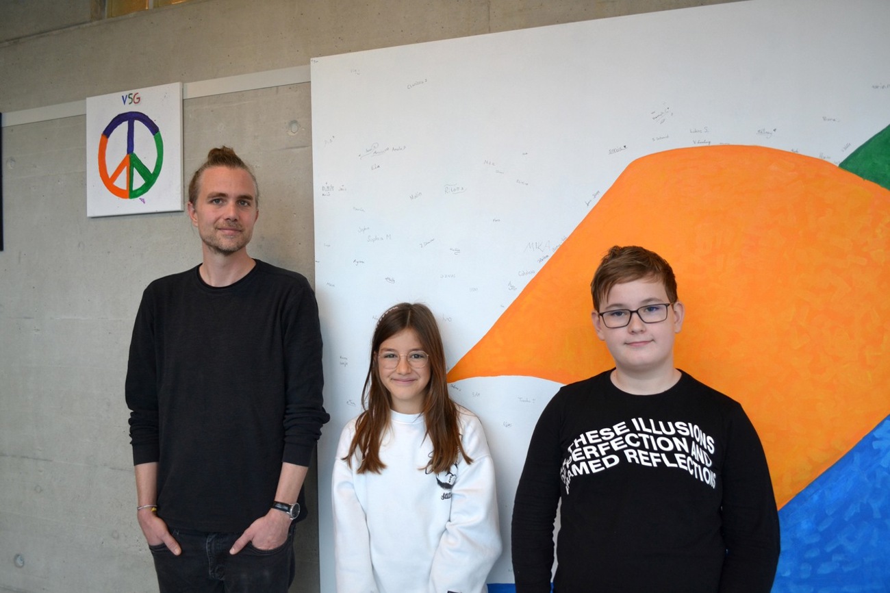 Schulsozialarbeiter Martin Koch bildet die Peacemaker der Primarschule in Tägerwilen aus. Mia und Robert haben die Ausbildung durchlaufen und auf dem Pausenplatz bereits erfolgreich Streit geschlichtet. Im Hintergrund das Bild der Friedenstaube, auf dem alle Schülerinnen und Schüler unterschrieben haben. Foto: Martina Seger-Bertschi